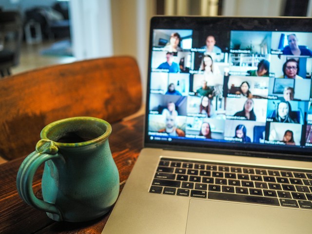 Online Meeting Ein Laptop mit einem laufenden Online-Meeting steht neben einer Tasse auf einem Tisch